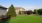 a large green lawn with a gazebo and trees and a building